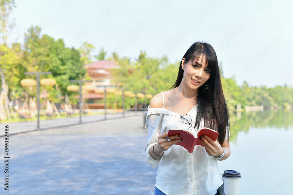 Education Concepts. Asian women reading books in the park. Beautiful women are relaxing in the park. Beautiful women are happy to read. Education Concepts. Asian women reading books in the park. Beautiful women are relaxing in the park. Beautiful women are happy to read.