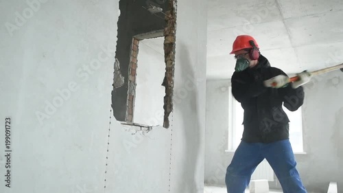 demolition work and rearrangement. worker with sledgehammer at wall destroying