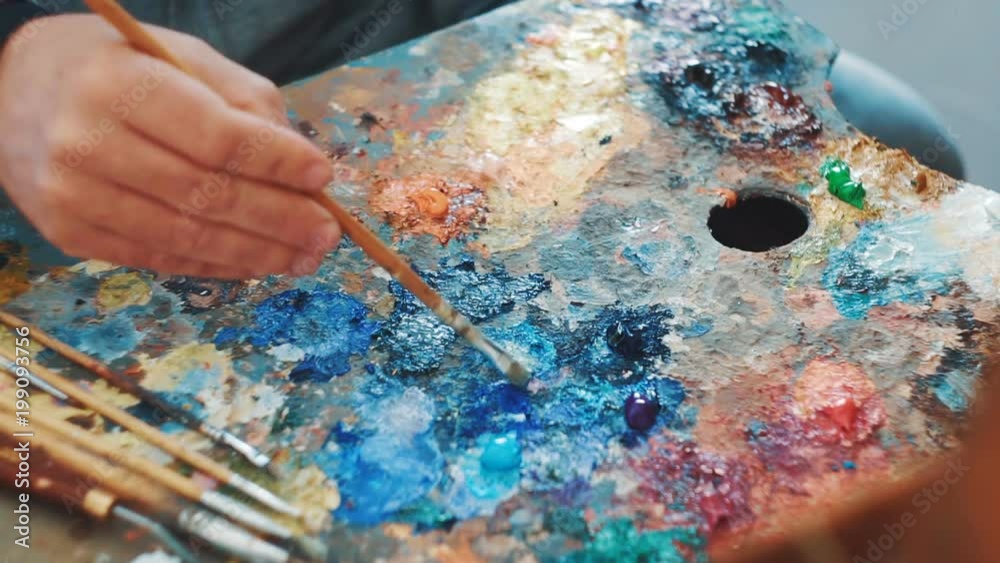 Artist mixes paints on the palette before painting a picture Artist mixes paints on the palette before painting a picture