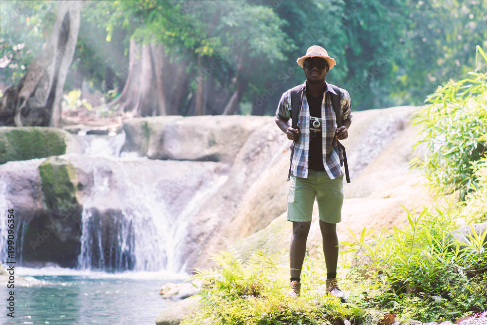 African Man Traveler with backpack standing and relaxing freedom at waterfall African Man Traveler with backpack standing and relaxing freedom at waterfall