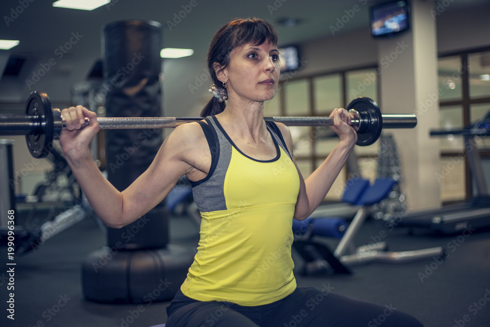 fitness exercises, a woman performs an exercise bar bench press on the shoulders