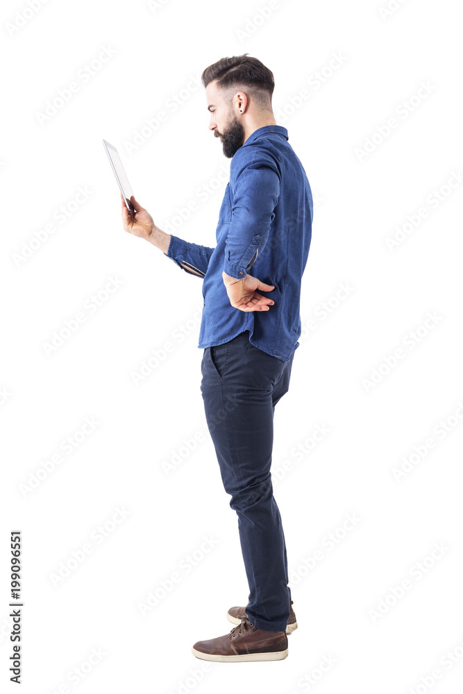 Profile view of serious bearded businessman holding and looking at tablet computer. Full body isolated on white background. Profile view of serious bearded businessman holding and looking at tablet computer. Full body isolated on white background.