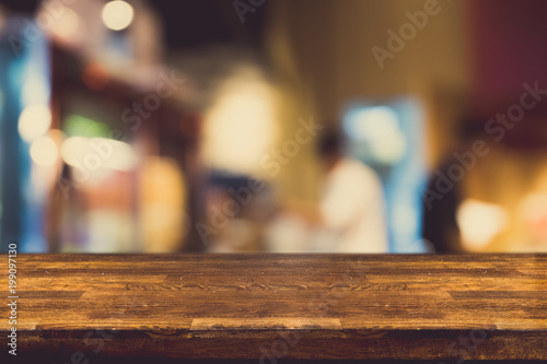 Empty dark wood table top and blur of cafe or restaurant in dark night background. For montage product display