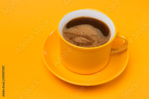 a yellow cup on a yellow saucer, coffee with foam, on a yellow background © aneduard