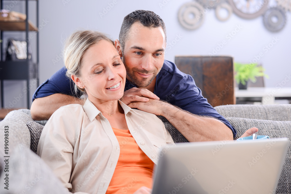 portrait of a young couple relaxed at home in sofa websurfing on internet with laptop computer portrait of a young couple relaxed at home in sofa websurfing on internet with laptop computer