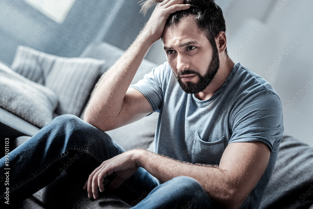 Absolutely hopeless. Depressed unhappy cheerless man holding his forehead and thinking what to do while being in a hopeless situation Absolutely hopeless. Depressed unhappy cheerless man holding his forehead and thinking what to do while being in a hopeless situation