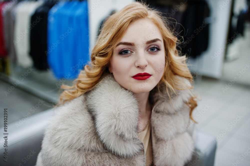 Elegance blonde girl in fur coat at the store of fur coats and leather jackets.