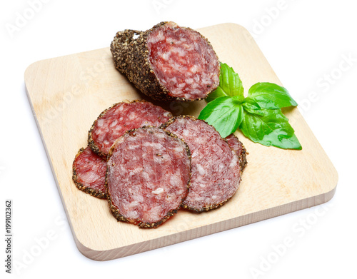 Dried organic salami sausage covered with pepper on wooden serving board