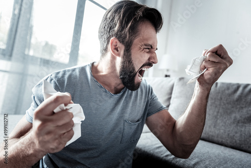 Nervous breakdown. Angry unhappy emotional man holding crumpled paper and crying while expressing his emotions photo