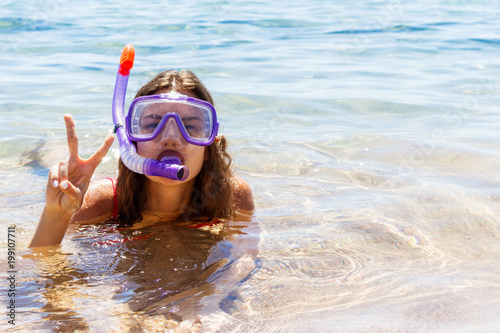 Beach vacation fun woman wearing a mask tube for swimming in ocean water. Close-up portrait of a girl in her travel holidays