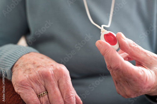 Close Up Of Unwell Senior Woman Holding Personal Alarm Button At Home