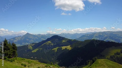 trees overview. aerial view of Tirol Austria Alpine mountains valleys hills forests trees and a cable car station on a summer day with blue sky and white clouds. drone footage