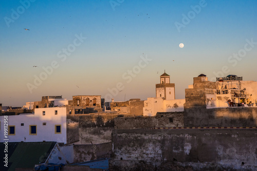 Full moon rising during sunset mosque in Essaouira, Morocco