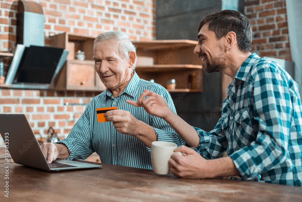 Positive aged man holding a credit card Positive aged man holding a credit card