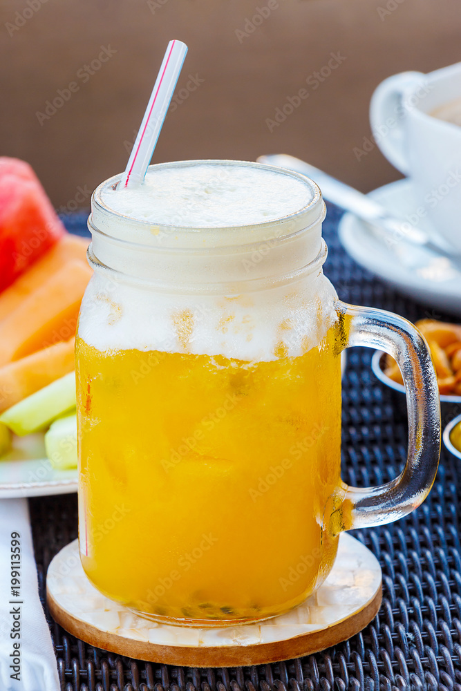 Tropical cocktail, mocktail, juice, refreshing drink from passion fruit in glass jar on table in cafe. Nuts, peanuts, olives, cappuccino coffee and fruits background. Tropical cocktail, mocktail, juice, refreshing drink from passion fruit in glass jar on table in cafe. Nuts, peanuts, olives, cappuccino coffee and fruits background.
