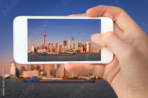 Closeup of a hand with smartphone taking a picture of Shanghai skyline and the Huangpu river  China