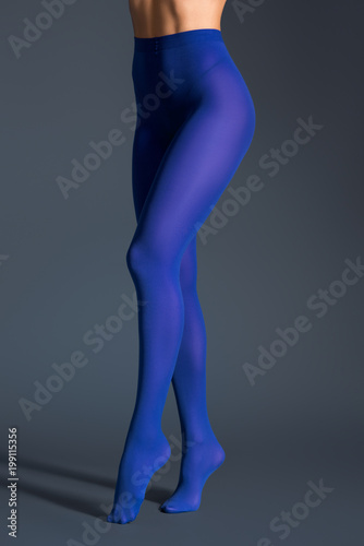 Slim woman in blue pantyhose on dark background