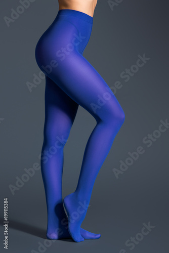 Картината върху платно Female legs in blue pantyhose on dark background