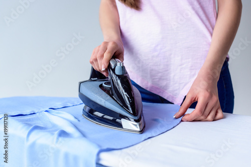 cropped shot of woman ironing shirt at home