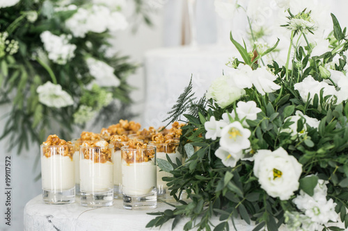 Desserts served in glasses besides white bouquet of flowers