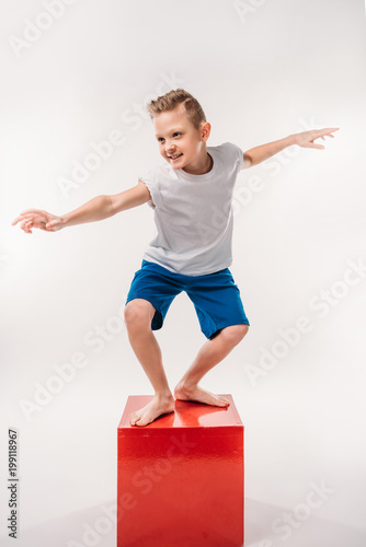 Fotografie smiling boy pretending to be a surfer, isolated on white