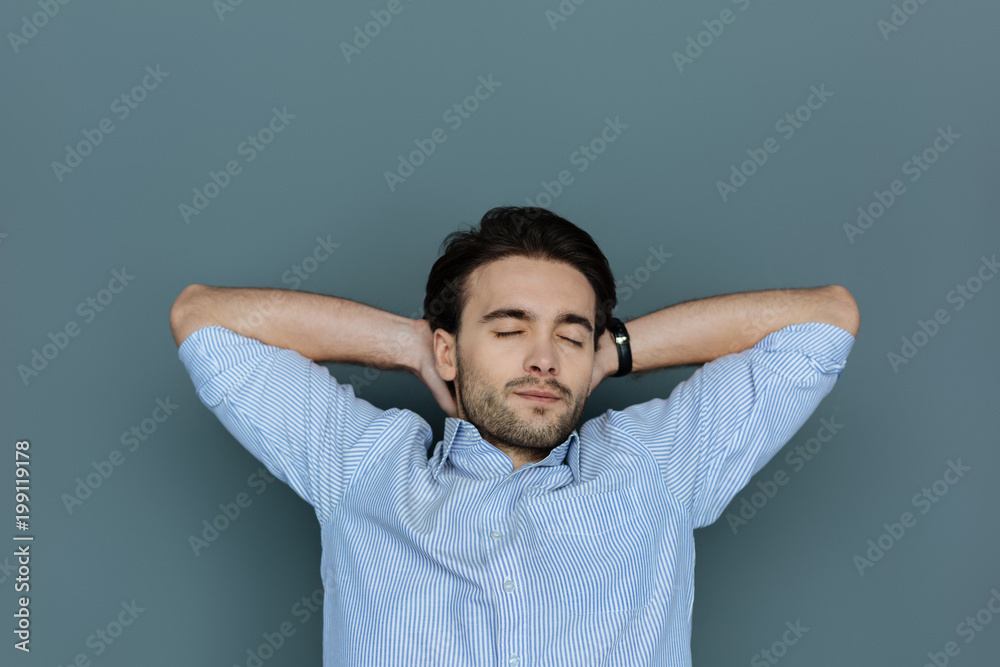Time to relax. Pleasant nice handsome man closing his eyes and resting while putting hands under his head Time to relax. Pleasant nice handsome man closing his eyes and resting while putting hands under his head