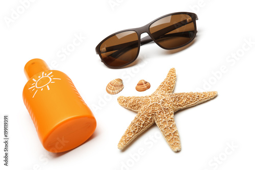 Bottle of suntan cream with sunglasses and starfish isolated on white