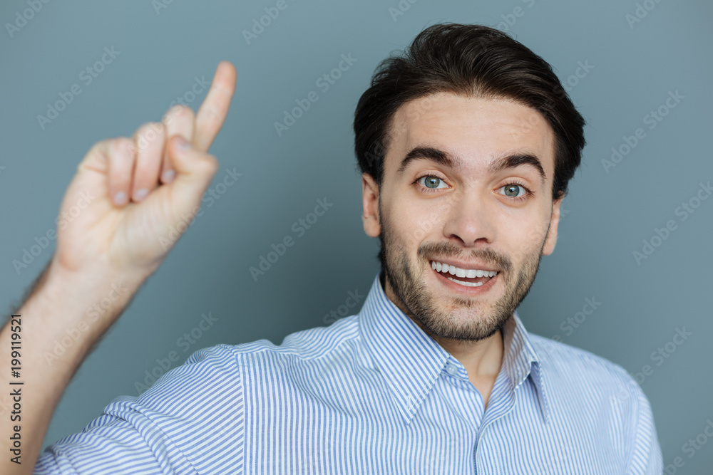 Creative idea. Cheerful pleasant smart man smiling and pointing up with his finger while finding a solution to the problem Creative idea. Cheerful pleasant smart man smiling and pointing up with his finger while finding a solution to the problem