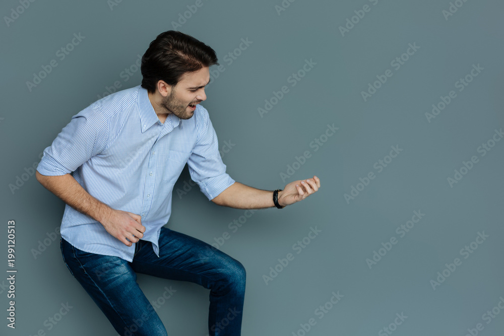 Music composer. Cheerful positive nice man holding a musical instrument and playing it while being involved in the process Music composer. Cheerful positive nice man holding a musical instrument and playing it while being involved in the process