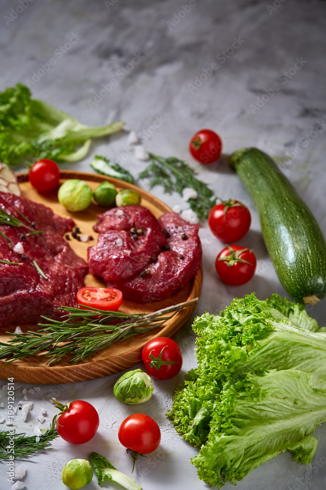Still life of raw beef meat with vegetables on wooden plate over white background, top view, selective focus Still life of raw beef meat with vegetables on wooden plate over white background, top view, selective focus