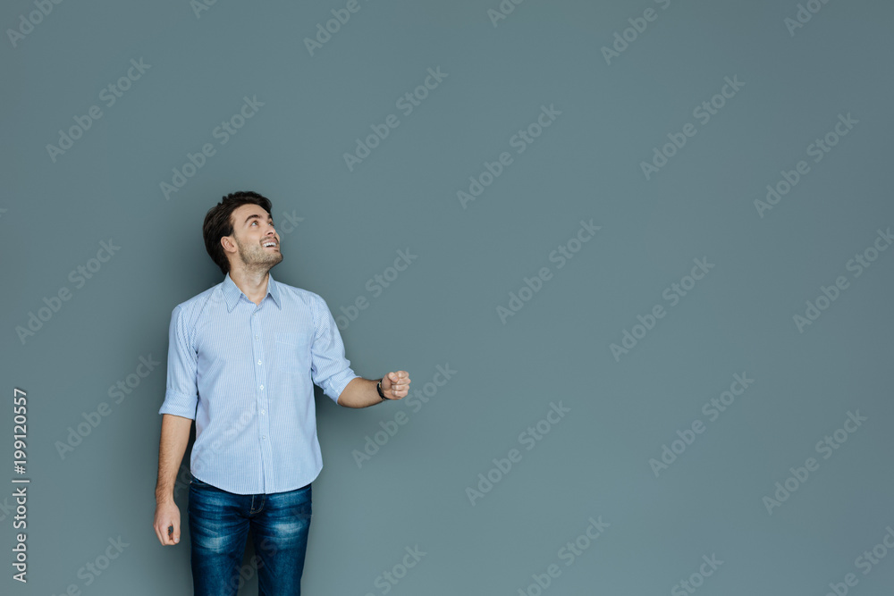 It is raining. Joyful nice delighted man looking at the sky and smiling while holding an umbrella It is raining. Joyful nice delighted man looking at the sky and smiling while holding an umbrella