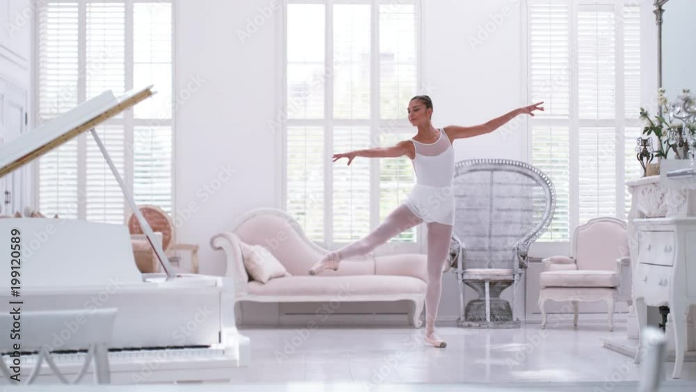 Graceful ballerina practicing ballet in white studio, slow motion Graceful ballerina practicing ballet in white studio, slow motion