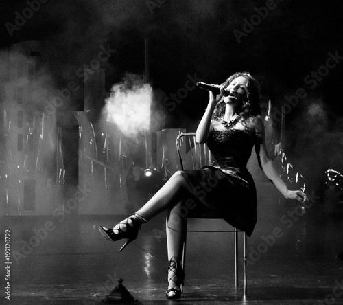 young pretty woman with sexy stylish cloth singing into microphone in retro dress, black and white