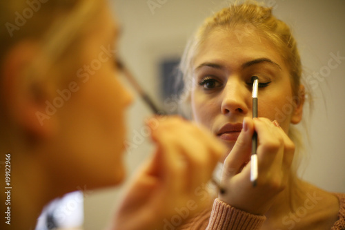 Blonde woman putting on make up in the morning.
