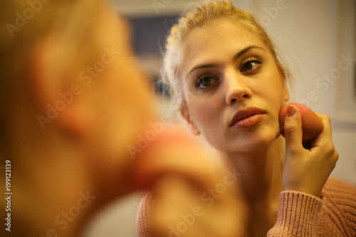 Beautiful woman applying powder on her face.