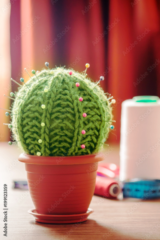 Cactus as a handmade needle bed on table. Sewing accessories, colored spools of thread Cactus as a handmade needle bed on table. Sewing accessories, colored spools of thread