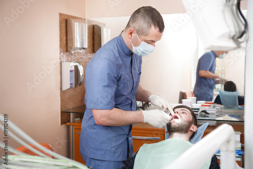 The doctor in the dentist s office examines the patient.