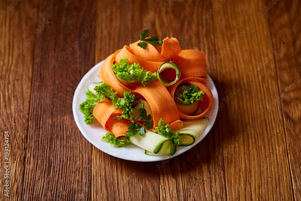 Artistically served vegetable salad with carrot, cucumber, letucce over wooden background, selective focus Artistically served vegetable salad with carrot, cucumber, letucce over wooden background, selective focus