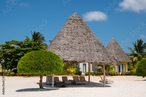 Bamboo hut with Beach bed among palm trees at perfect tropical coast fresh green palm trees around standing at the white sand beach and cloudless blue sky on a sunny day. Spa concept. © Svetlin