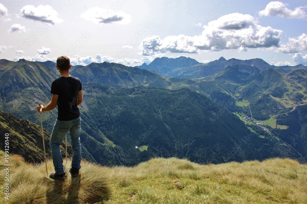 Trekker enjoying the view on the valley (Upper Seriana Valley). Orobie Alps, Lombardy, Italy