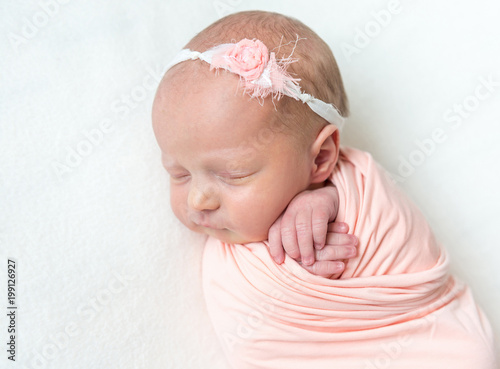 Sleeping newboen baby in a pink wrap photo