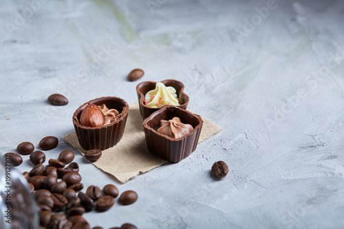 Sweet chocolate candies with coffee beans over white textured background, selective focus, close-up. photo