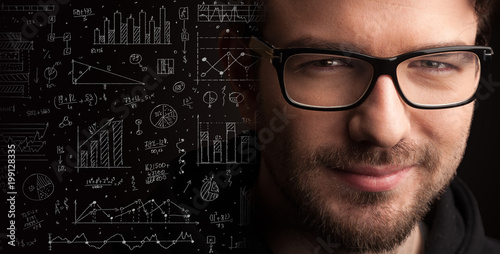 Portrait of a young businessman with charts and graphs scribbled next to him on a dark background