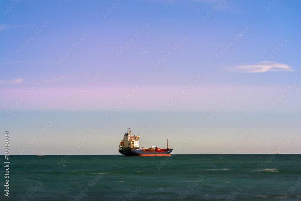 Lonely boat in mediterranean sea. Sea of green color contrasts with red colors of the ship. Blue sky