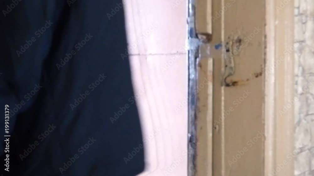 Caucasian man in black coat opening old wooden door and go away. Aged house interior, brown walls and rusty handle.