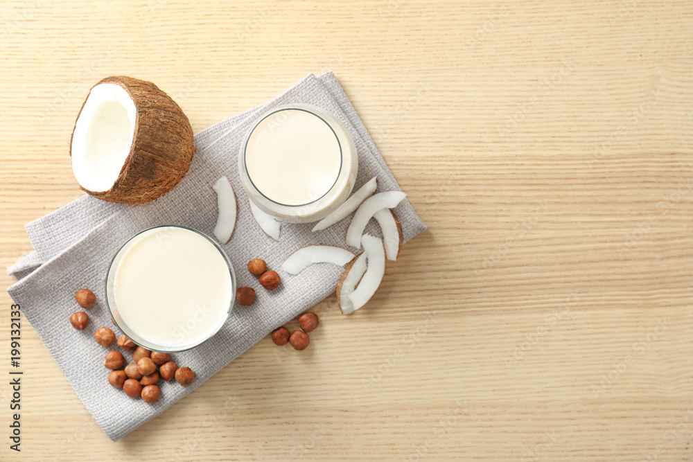 Glasses with milk substitute and nuts on wooden background, flat lay Glasses with milk substitute and nuts on wooden background, flat lay