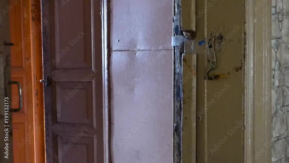 Old wooden door opening and closing. Aged house interior, brown walls and rusty handle. No people.
