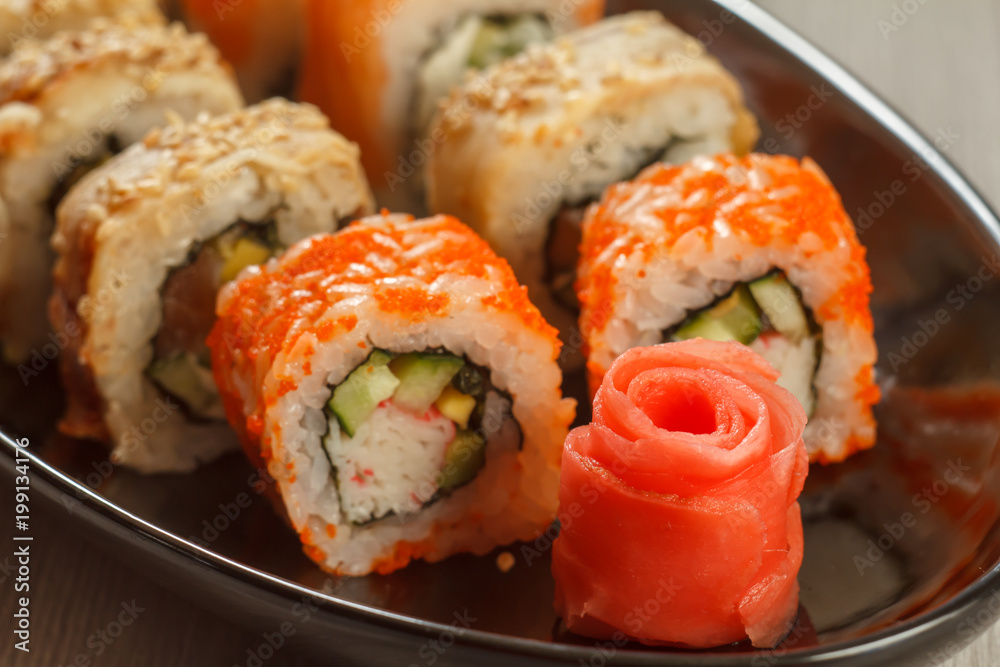Close up pickled ginger in the form of red rose and sushi rolls - Uramaki California, Uramaki with Conger on the background. Japanese cuisine Close up pickled ginger in the form of red rose and sushi rolls - Uramaki California, Uramaki with Conger on the background. Japanese cuisine