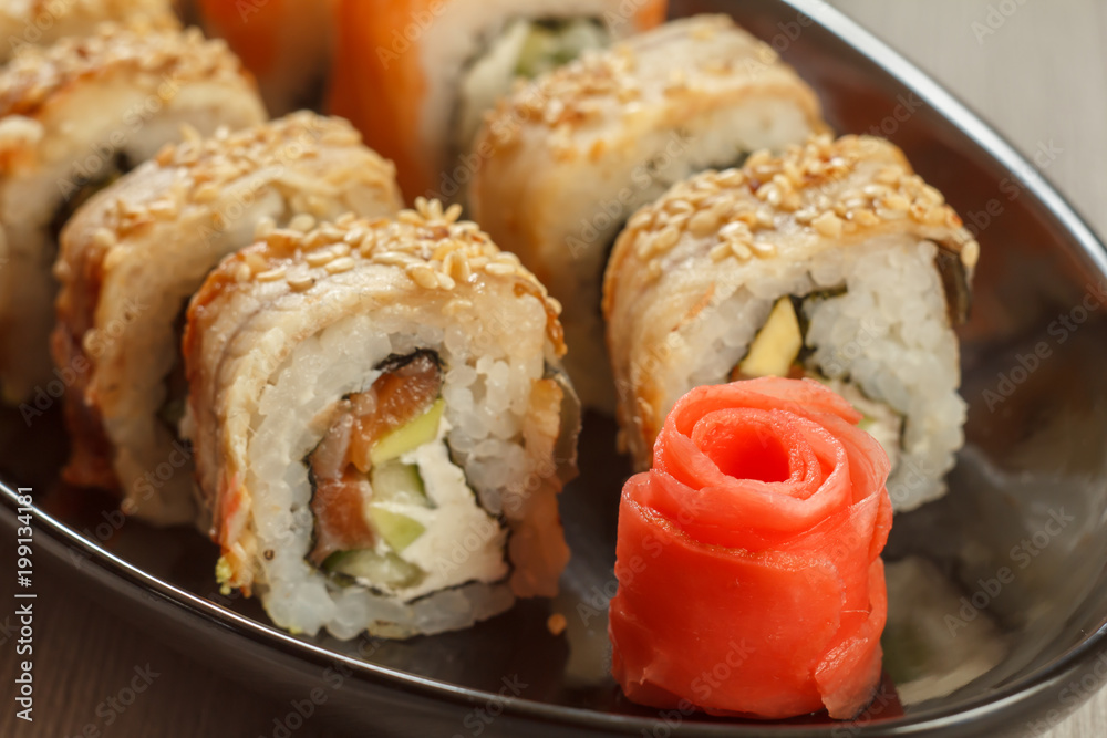 Close up pickled ginger in the form of red rose and sushi rolls - Uramaki with Conger on the background. Japanese cuisine Close up pickled ginger in the form of red rose and sushi rolls - Uramaki with Conger on the background. Japanese cuisine