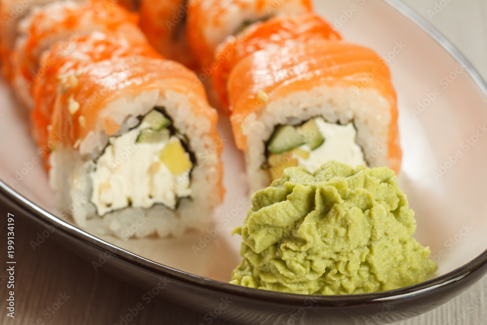 Close up wasabi and sushi rolls - Uramaki Philadelphia on the background. Japanese cuisine Close up wasabi and sushi rolls - Uramaki Philadelphia on the background. Japanese cuisine